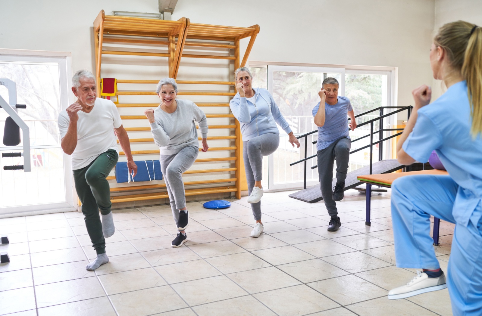 A group of seniors being led in a light exercise by a senior living staff member.