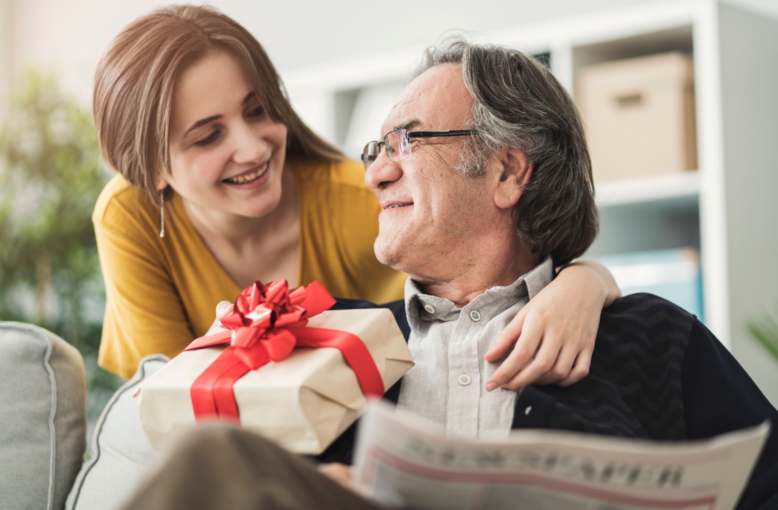 A senior man receives a birthday gift from his daughter