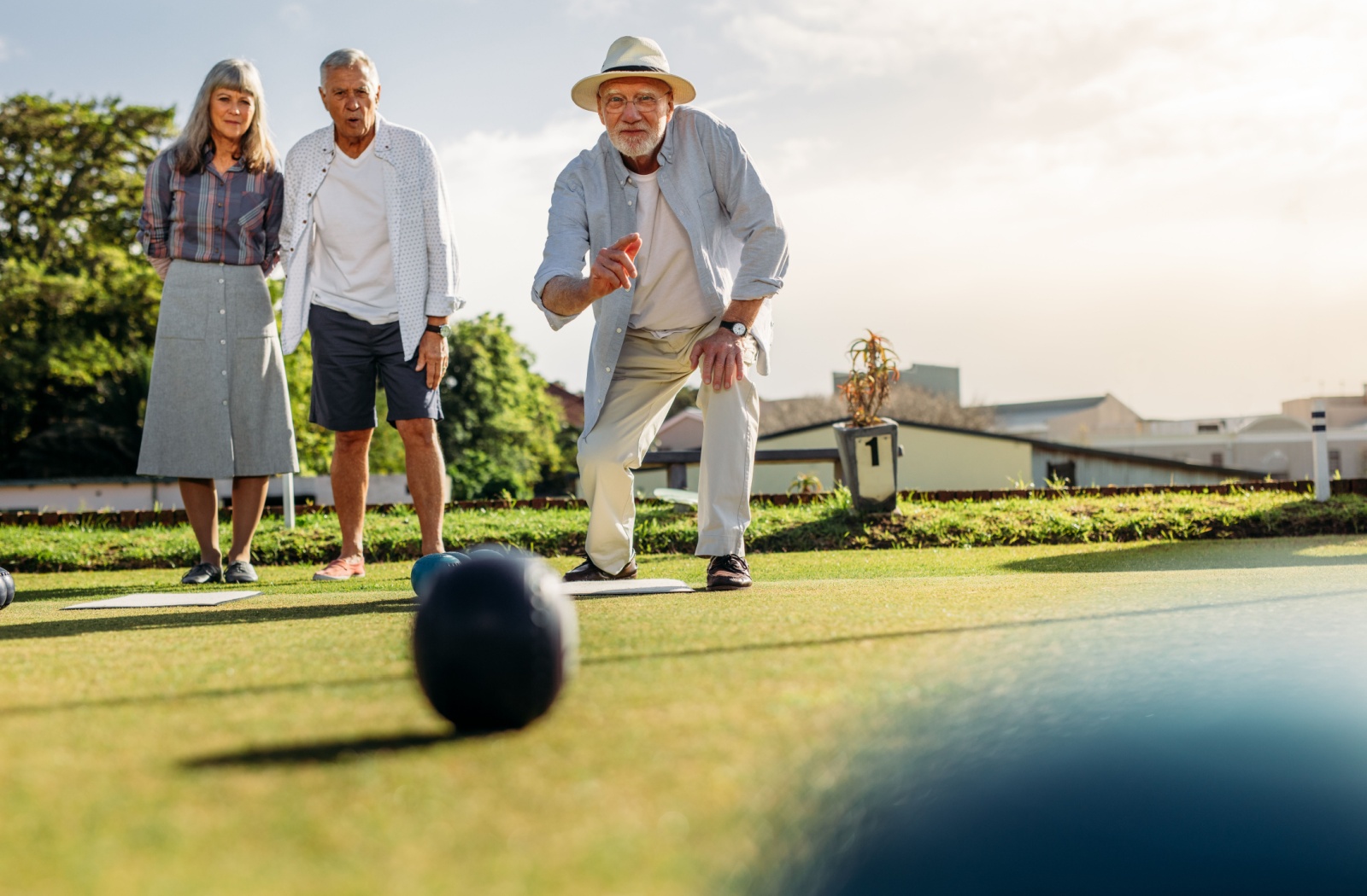 A group of seniors playing lawn bowling outside on a sunny day