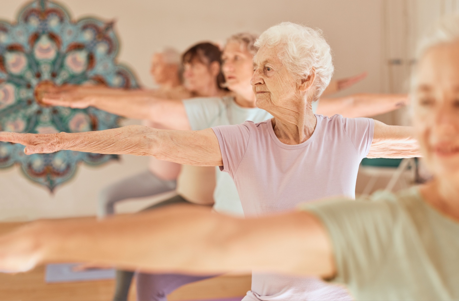 A group of seniors practice yoga in a well-lit studio.