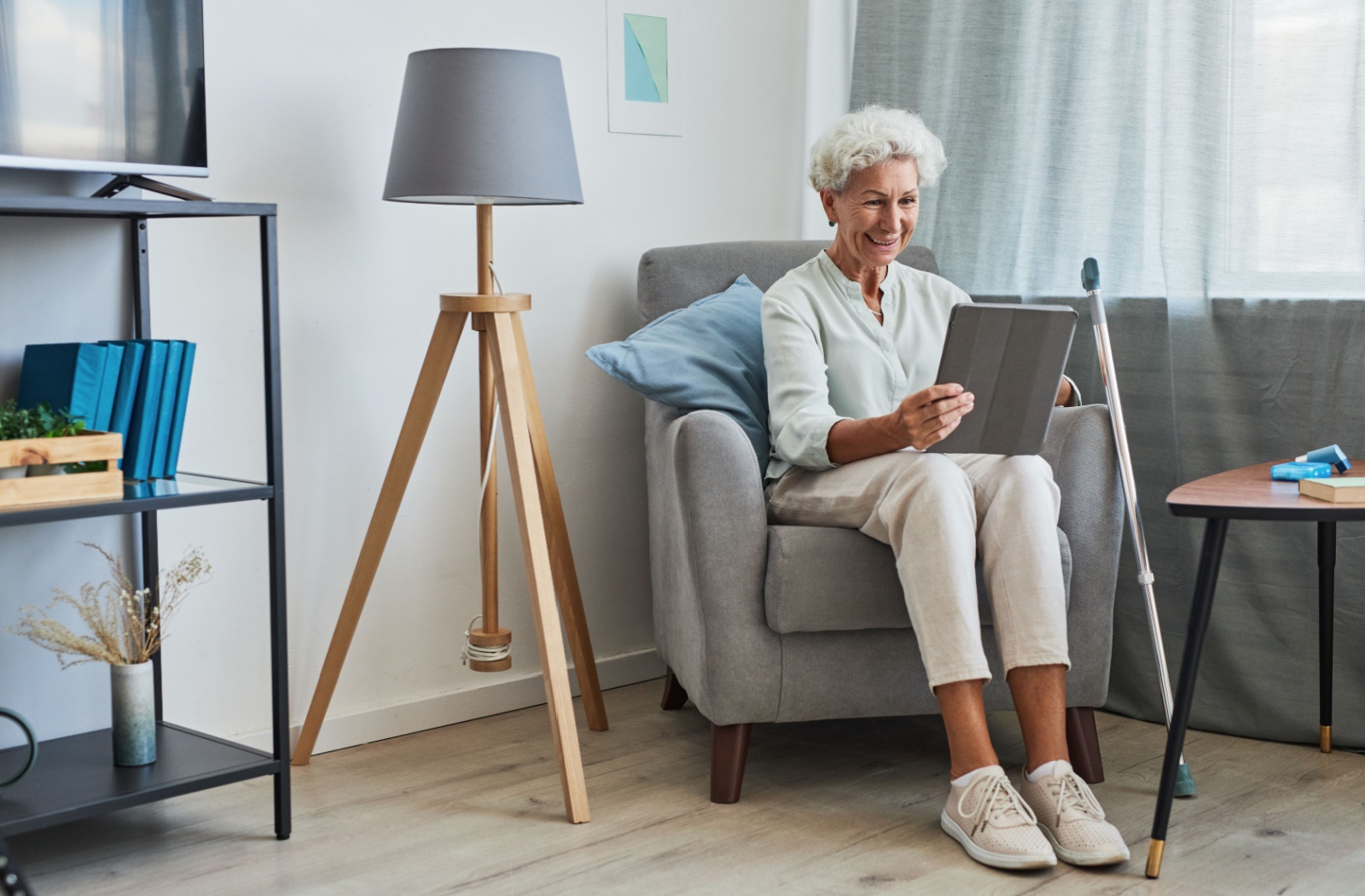 A smiling senior woman using a digital tablet at home while sitting comfortably in an armchair.