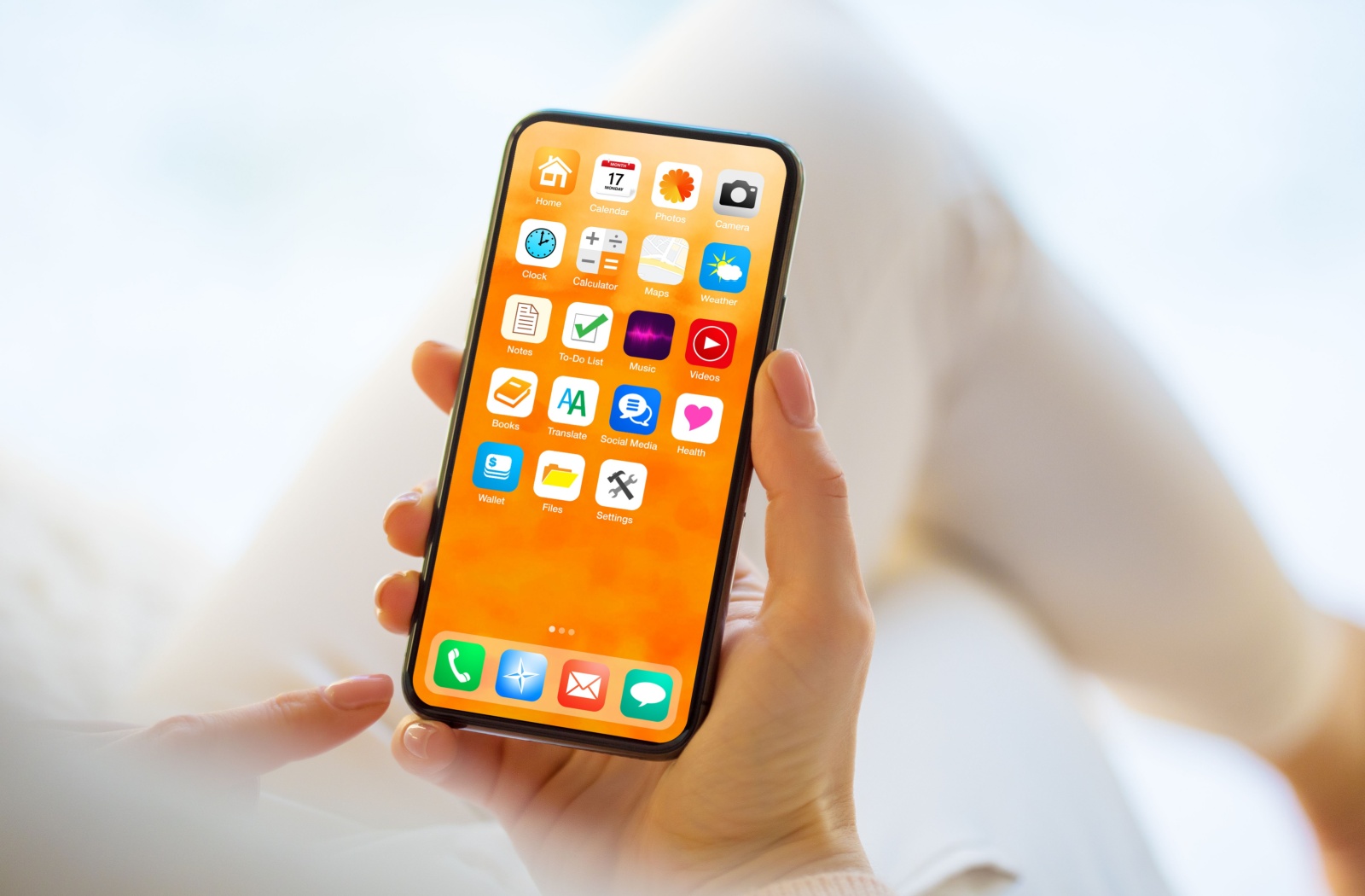 Close-up of a phone being held by a sitting individual. The phone's home screen shows different everyday app icons.