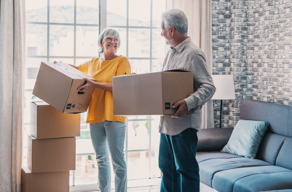An older couple smiles at one another while unpacking boxes in their new apartment in assisted living