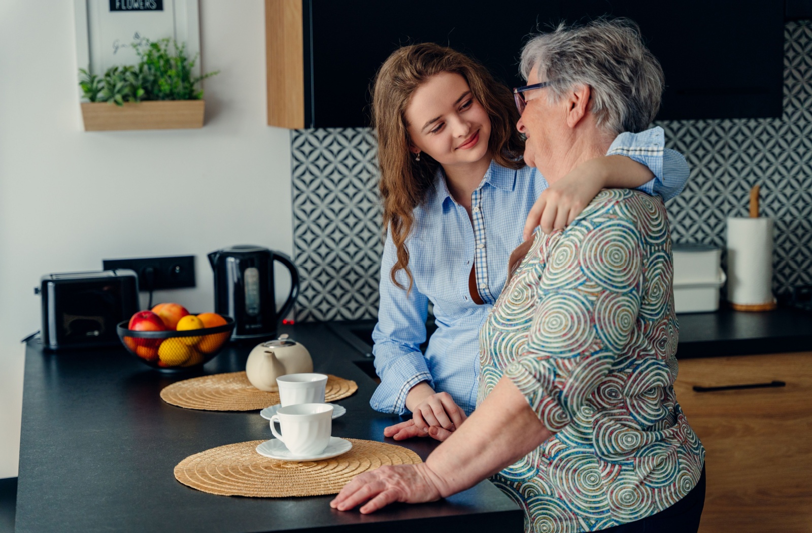 Younger adult and senior relative enjoy tea while sharing meaningful in a family conversation