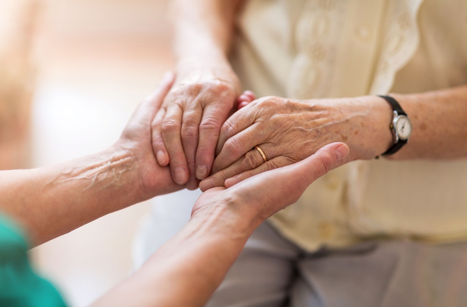 A close up of a caregiver holding both hands with a senior resident with MCI.
