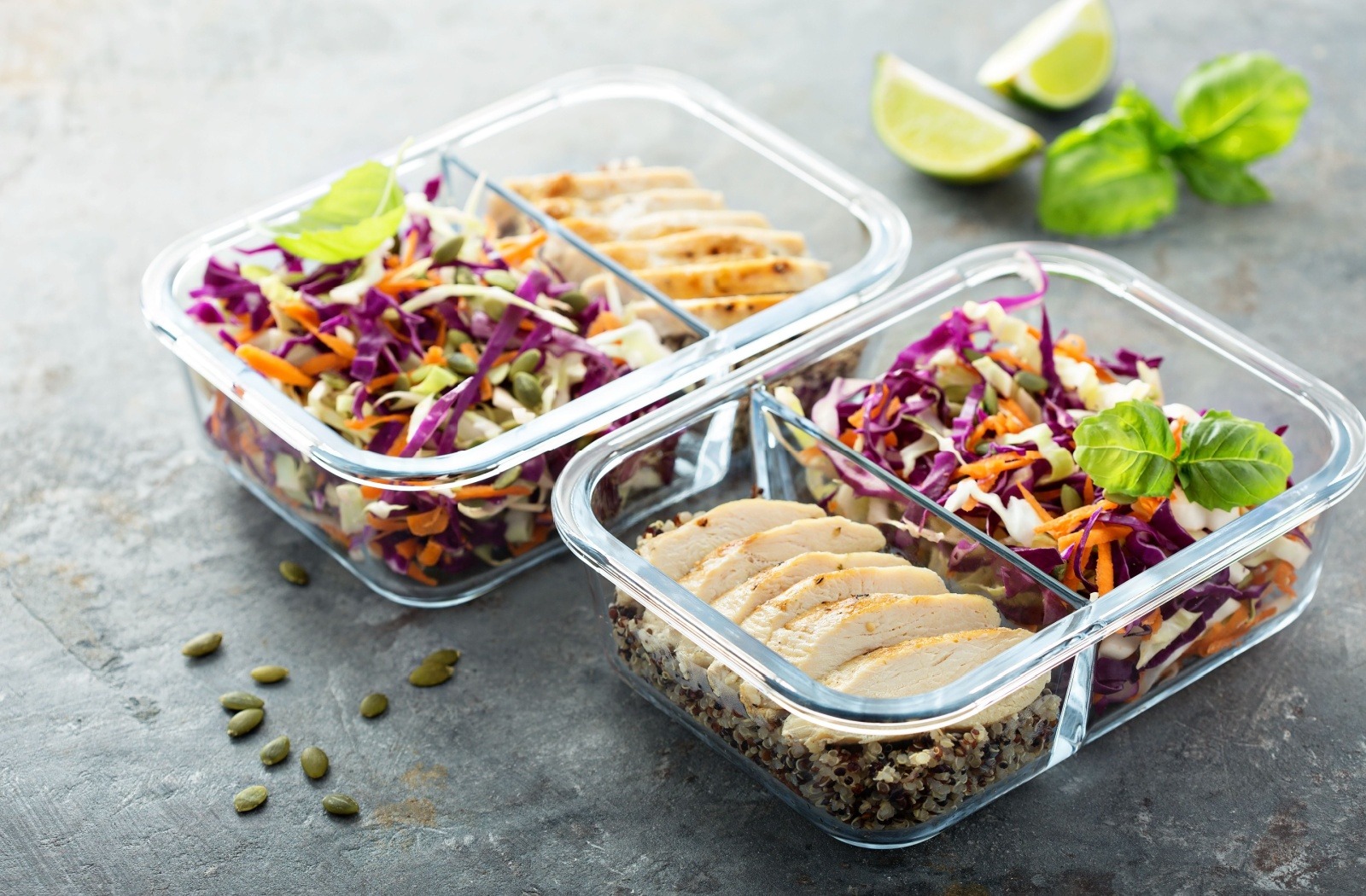 Two glass meal prep boxes containing cabbage salad, grilled chicken, and quinoa.