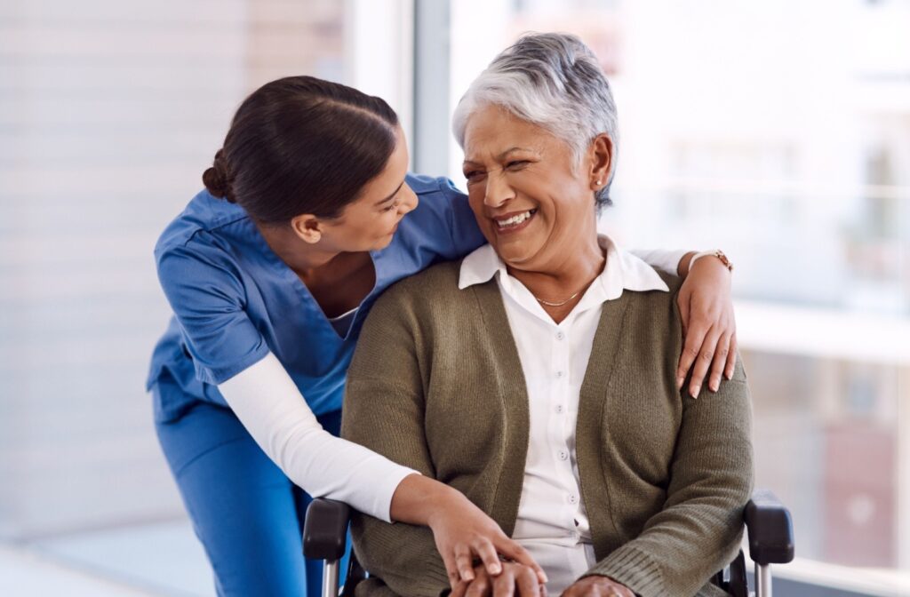 A caregiver hugs a smiling senior respite care resident.